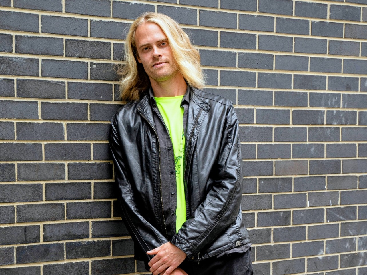 Kim leaning on a brick wall